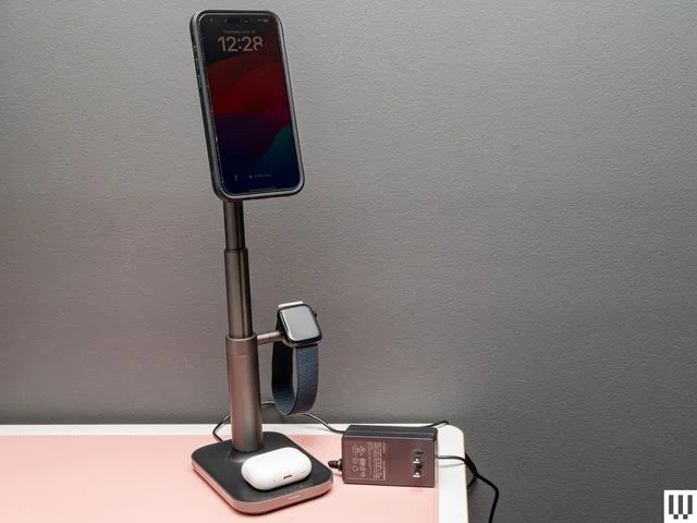 Mophie MagSafe 3-in-1 Extendable Wireless Charging Stand, a slender stand with square base, circular pad on top to hold a phone, and small extension on the side to hang a wristwatch.