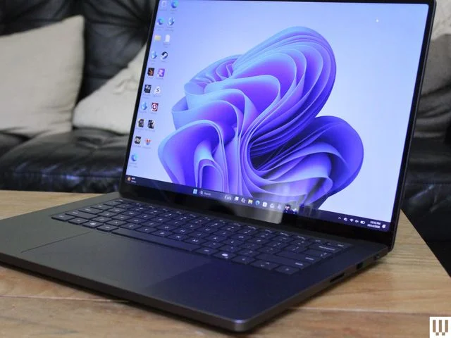Front of an open slim black laptop on a light wood table