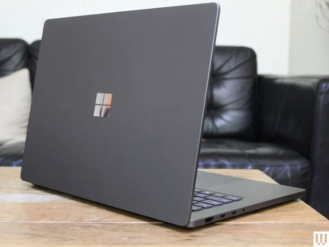 Back of a slim black laptop on a light wood table