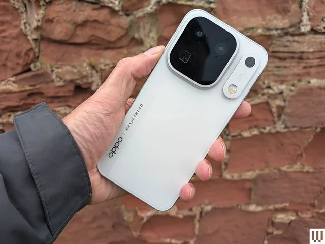 Hand holding a slim mobile phone showing the backside with large camera lenses
