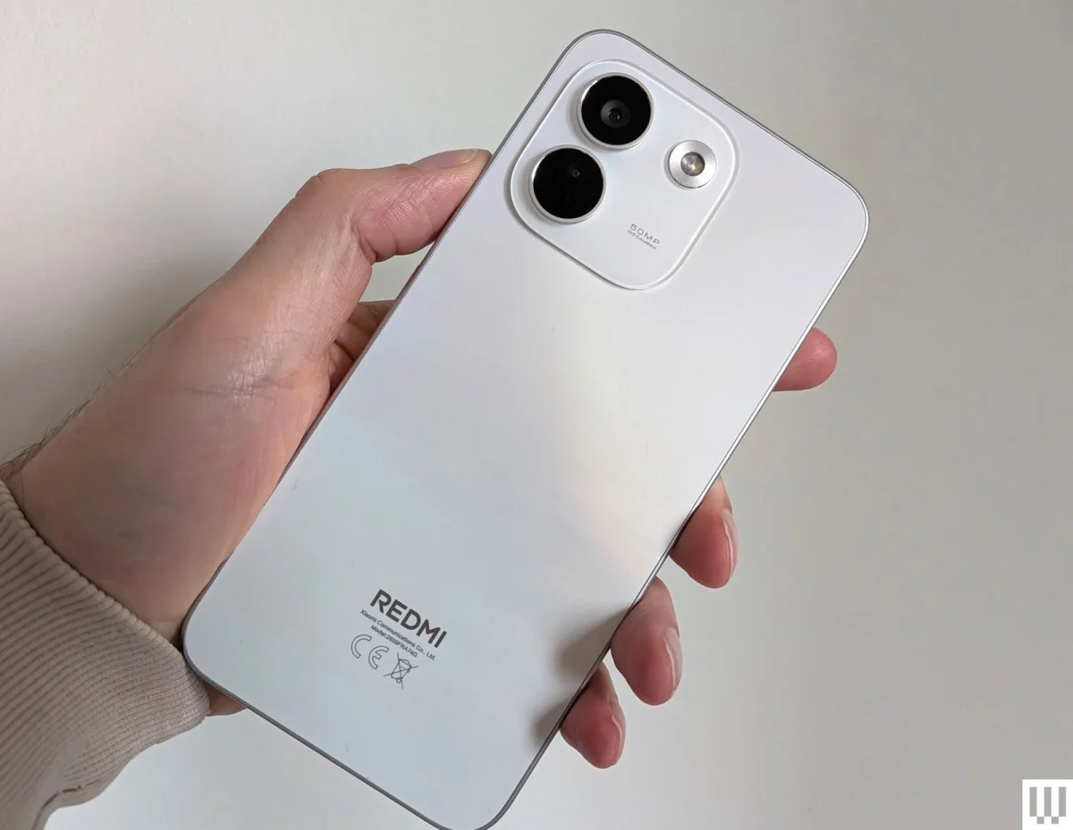 Hand holding a slim white mobile phone showing the rear cameras