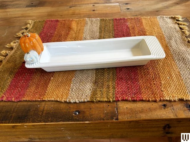 White ceramic tray with decorative mini pumpkin on the left ledge