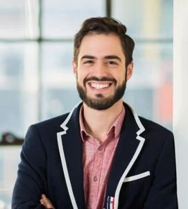 Sylvain Kalache, head of AI Labs at Rootly, smiling with arms crossed, wearing a navy blazer with white piping.